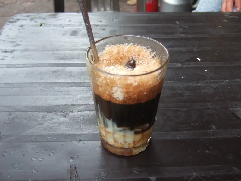 A glass of cà phê sữa đá, iced coffee layered over condensed milk